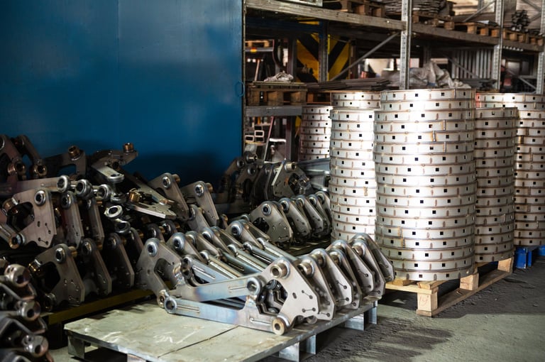 A factory storage area filled with stacks of industrial metal parts and components